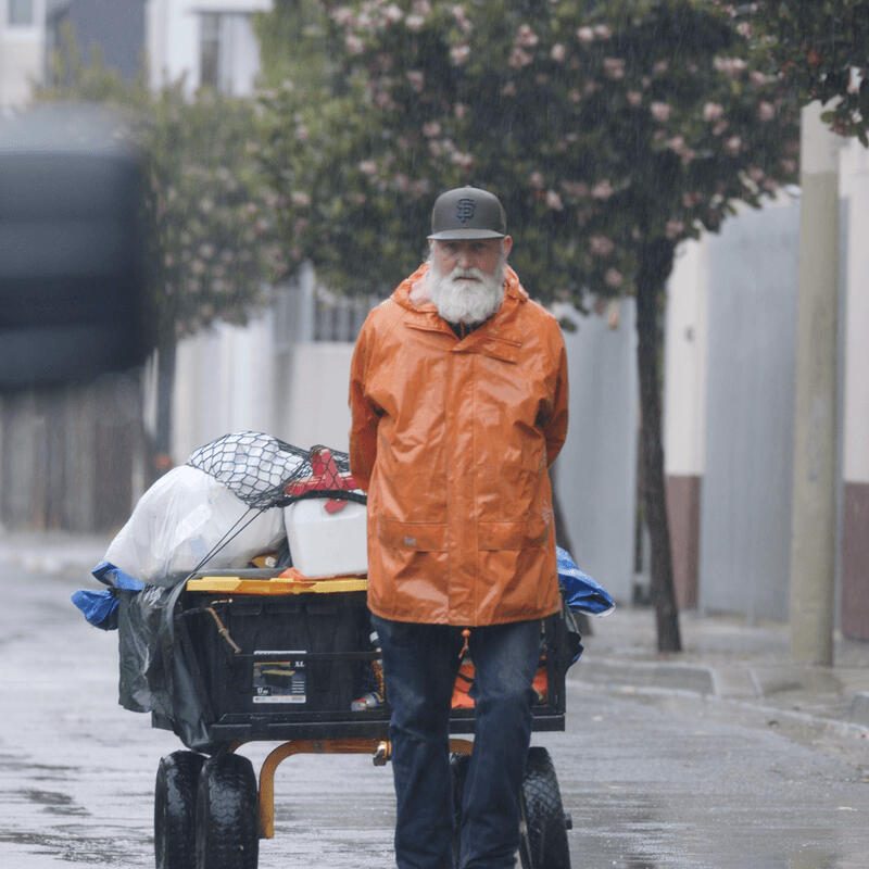 Paul pulling cart full of dog food and supplies in the rain.